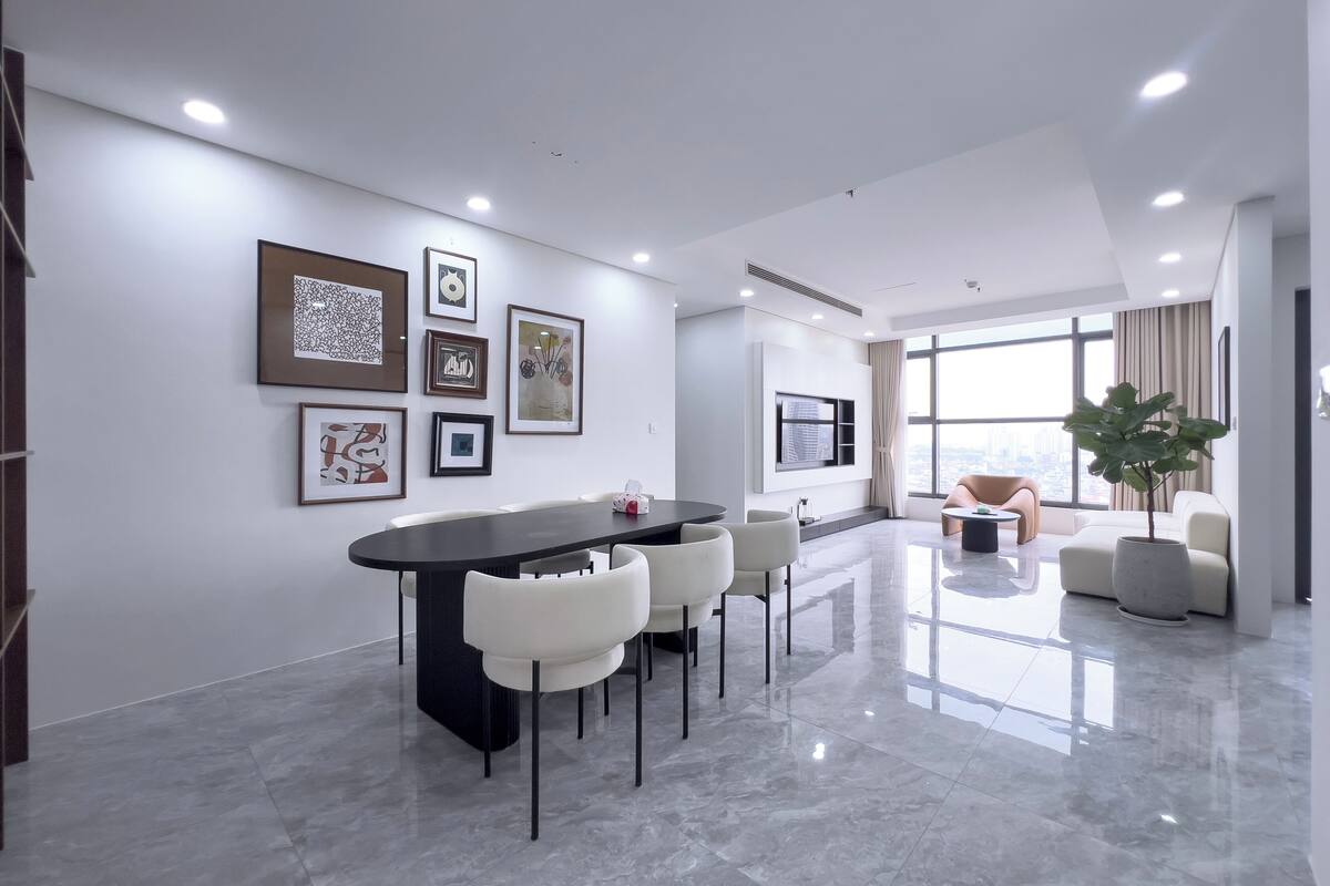 A modern interior with a dining area, a sofa, and a large window offering a city view.
