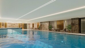 An indoor swimming pool with a reception area, seating, and a wall with a logo.