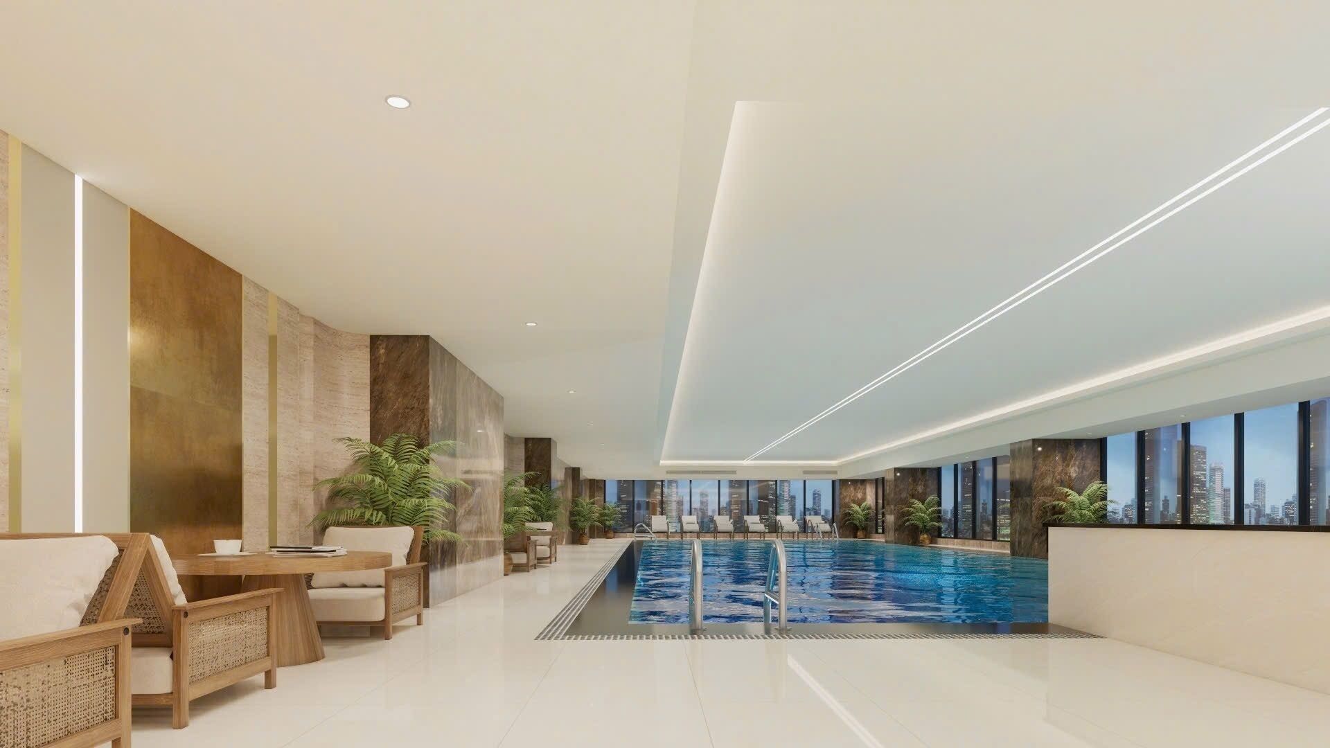 A modern indoor swimming pool with a city view, surrounded by lounge seating and potted plants.