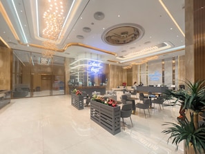 A modern hotel lobby with a reception desk, seating area, and a neon sign for the Arabelle Suites. - Capital Elite Luxury Residences (Ha Noi)