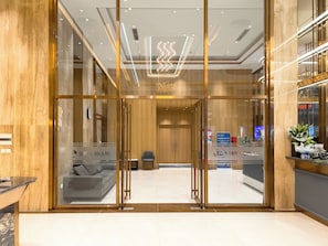 A hotel lobby with a reception desk, a seating area with a sofa, and a chandelier. - Capital Elite Luxury Residences (Ha Noi)