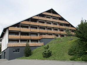 A multi-story building with a sloped roof, wooden balconies, and a hillside location. - La Prada, (Laax Dorf), 20047 by Interhome (Laax)