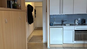 Uma cozinha moderna com armários brancos, pia de aço inoxidável e forno embutido.