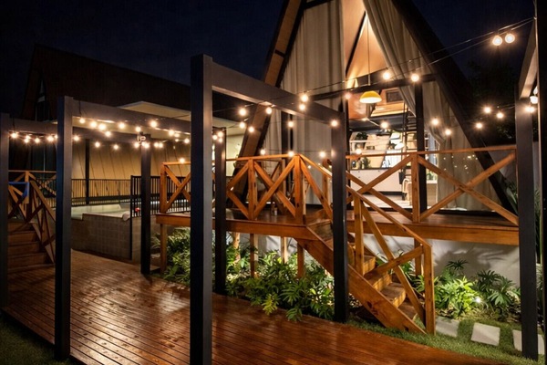 Espaço externo com iluminação charmosa e vista para a cabana, ideal para aproveitar a noite ao ar livre.