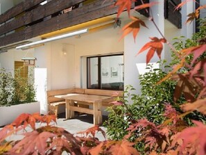 A modern interior with a wooden bench, a large window, and indoor plants. - Apartment  by Interhome (Laax)