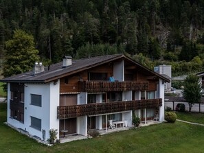 A two-story house with a balcony, a garage, and a small garden.