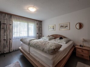 A bedroom with a bed, a nightstand, a lamp, and two framed pictures on the wall.