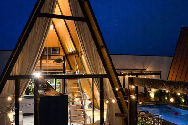 Vista noturna da cabana industrial com iluminação aconchegante e ambiente integrado, criando uma atmosfera perfeita para momentos especiais.