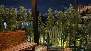 A brick fire pit with benches, string lights, and a view of the city at night. - Cabana Industrial com Hidro e Piscina Aquecida (Palhoça)