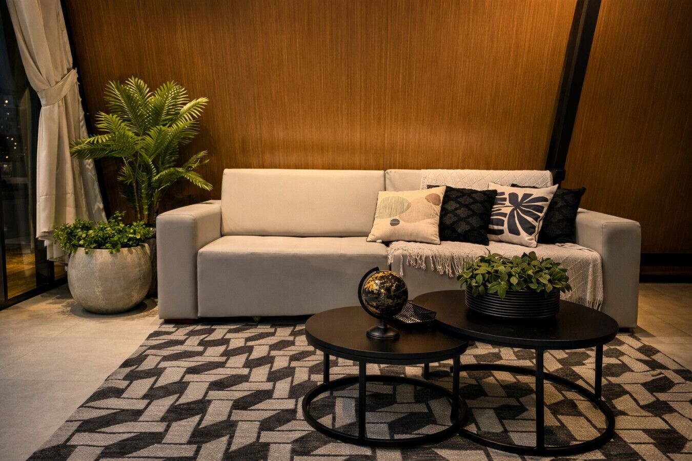 Un salon moderne avec un canapé, deux tables d’appoint, un globe terrestre et des plantes en pot.