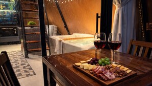 A wooden table with a cheese board, grapes, nuts, and cured meats, accompanied by two glasses of red wine. - Cabana Industrial com Hidro e Piscina Aquecida (Palhoça)