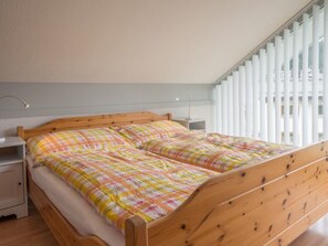 Et soveværelse med en træseng, et natbord, en lampe og et vindue med persienner.