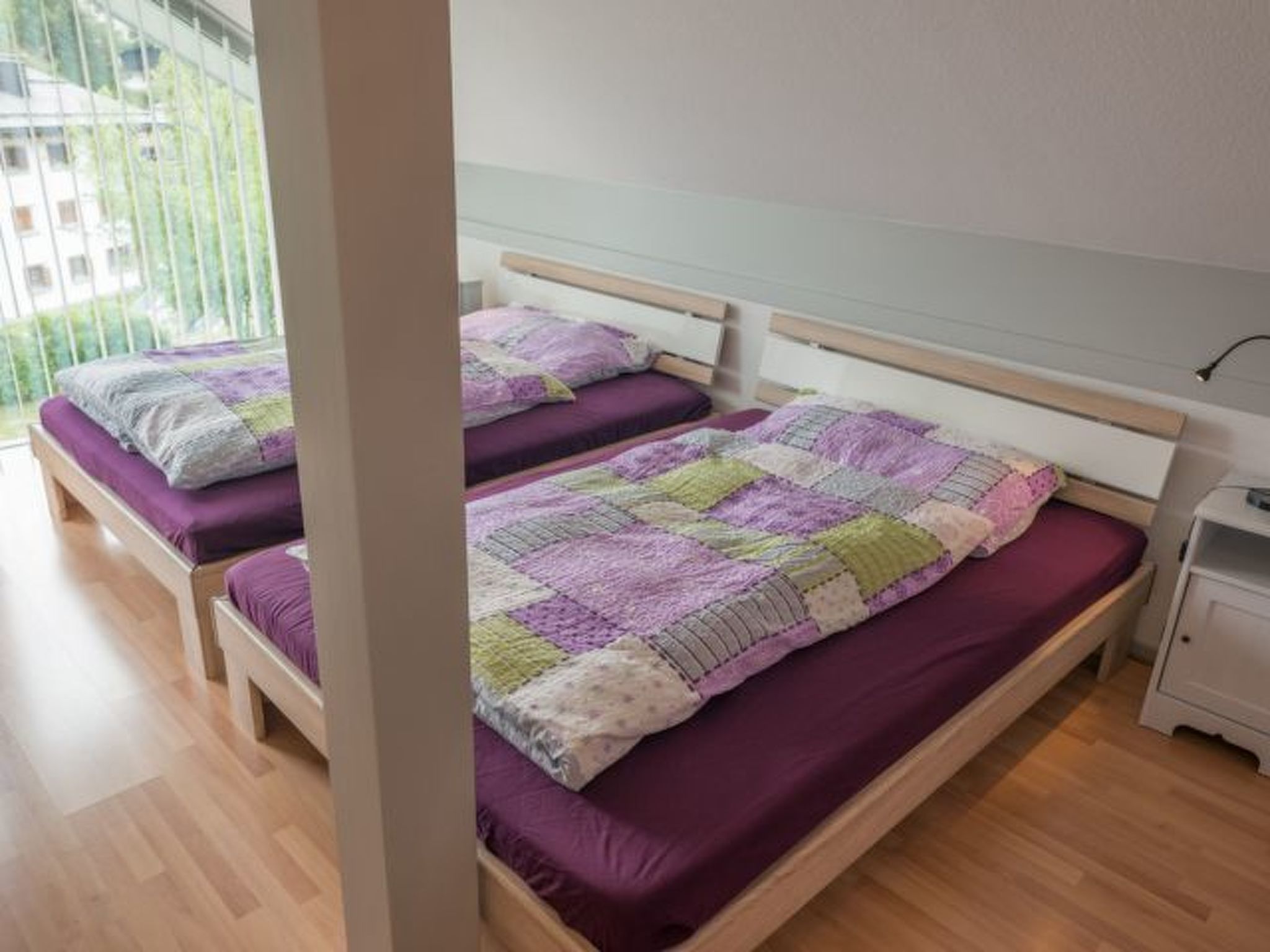 A bedroom with two beds, each with a purple bedspread and pillows.