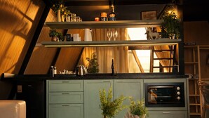 A kitchen with a built-in oven, a coffee machine, and a shelf with glassware. - Cabana Country Romântica com Banheira & Piscina (Palhoça)