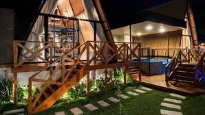 A modern, triangular-roofed building with a wooden deck and stairs leading to the entrance. - Cabana Country Romântica com Banheira & Piscina (Palhoça)