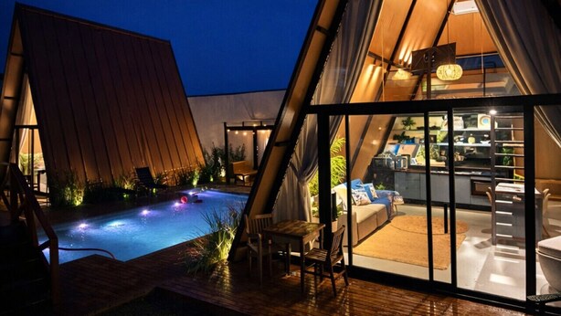 A modern, triangular-roofed building with a pool and outdoor seating area. - Cabana Praiana - Vivendas Ferreira (Palhoça)
