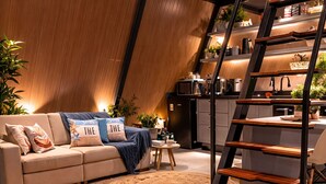 A modern living room with a hot tub, a sofa with decorative pillows, a coffee table, and a staircase leading to an upper level. - Cabana Praiana - Vivendas Ferreira (Palhoça)