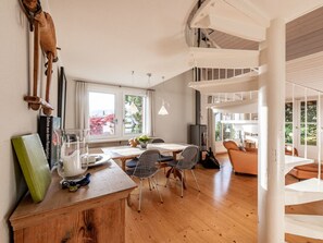 A spacious dining area with a wooden table and chairs, large windows, and a view of greenery outside. - Casa Daida, (Flims Dorf), 31 by Interhome (Flims)