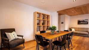 A dining area with a wooden table, chairs, a bookshelf, a sofa, and a painting on the wall. - Flem Mountain Lodge, (Flims Waldhaus), by Interhome (Flims)