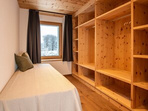 A bedroom with a bed, a window with curtains, and a wooden wardrobe. - Flem Mountain Lodge, (Flims Waldhaus), by Interhome (Flims)