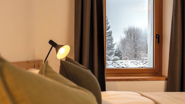 A bed with a window, a lamp, and a view of snow-covered trees. - Flem Mountain Lodge, (Flims Waldhaus), by Interhome (Flims)