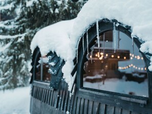 A snow-covered window with icicles hanging from the eaves, a wooden fence, and a blurred background with lights. - Flem Mountain Lodge, (Flims Waldhaus), by Interhome (Flims)
