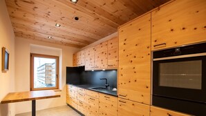 A modern kitchen with wooden cabinetry, a black countertop, and a built-in oven. - Flem Mountain Lodge, (Flims Waldhaus), by Interhome (Flims)