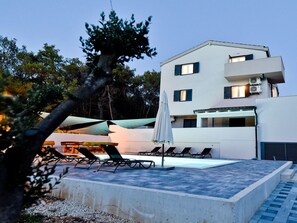 A modern building with a pool area, including lounge chairs and umbrellas. - Villa Pinia with pool, Zadar by Interhome (Crno)