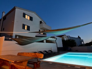 A modern building with a pool, outdoor furniture, and a hammock. - Villa Pinia with pool, Zadar by Interhome (Crno)