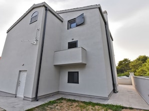 Ein modernes Gebäude mit flachem Dach, einem kleinen Balkon und einer Tür.