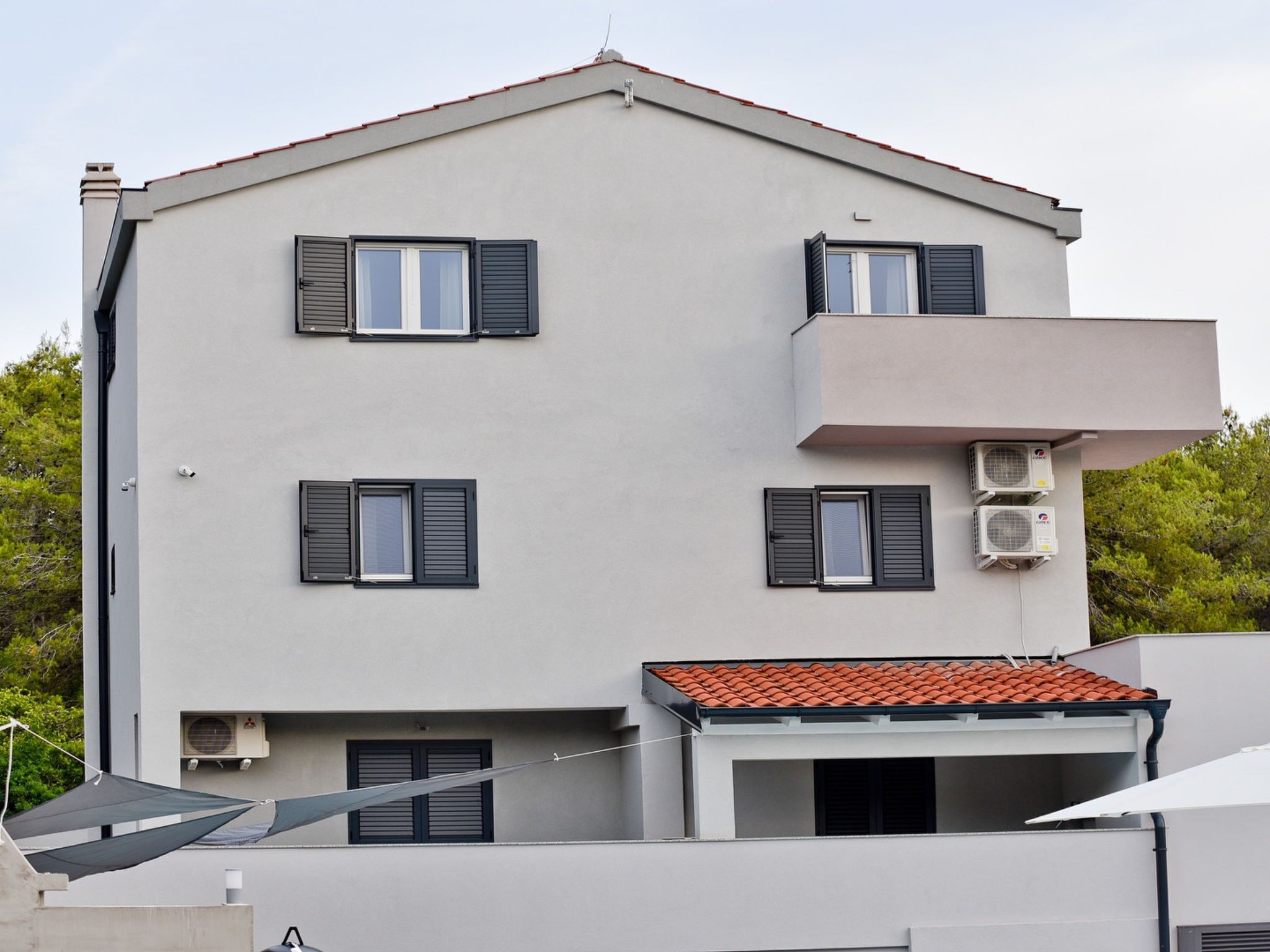 A multi-story building with a flat roof, multiple windows with shutters, and an air conditioning unit on the exterior wall.