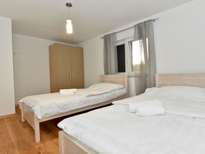 A hotel room with two single beds, a wardrobe, a window with curtains, and a hanging light fixture. - Villa Pinia with pool, Zadar by Interhome (Crno)