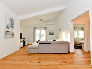 A spacious living area with a large sofa, wooden flooring, and a dining table. - Villa Pinia with pool, Zadar by Interhome (Crno)