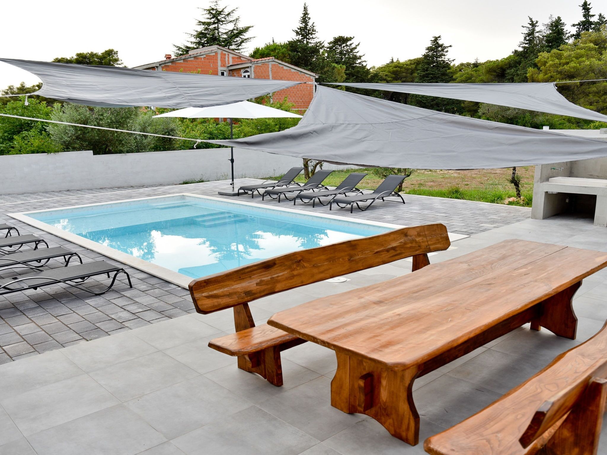 A swimming pool with lounge chairs and a wooden bench.