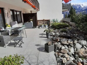 An outdoor patio with a dining set, a stone wall, and a mountain view. - Signinablick, (Laax Dorf), by Interhome (Laax)