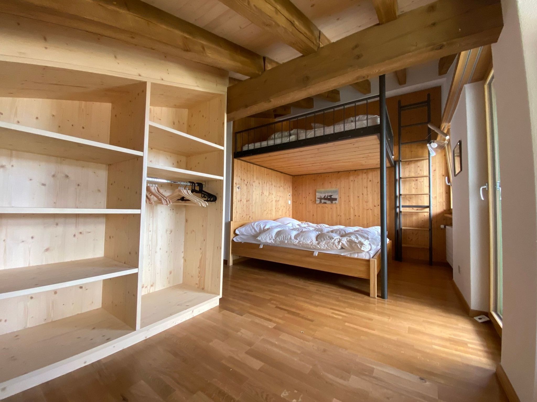 Una habitación con literas, estantes de madera y suelo de madera.