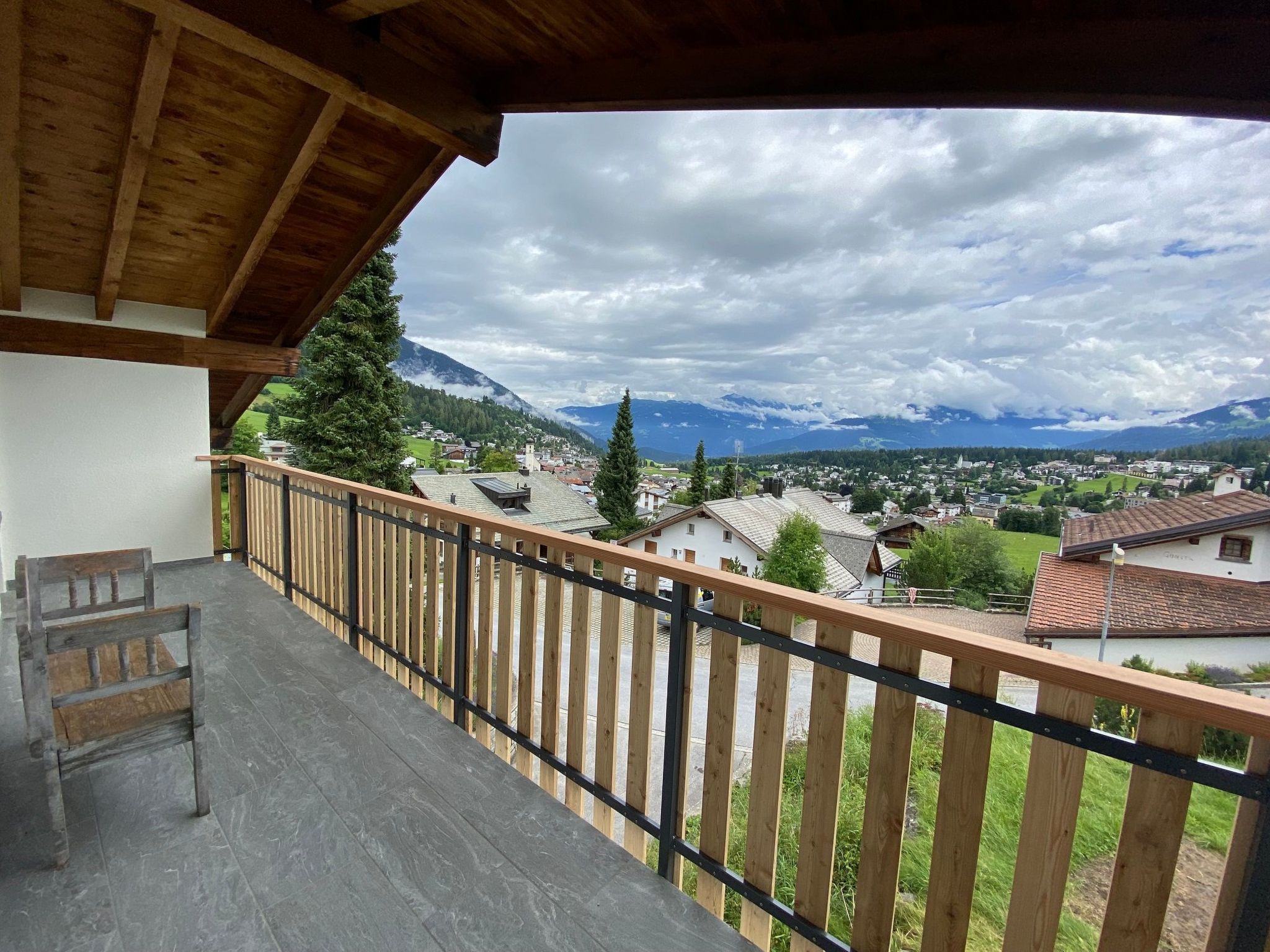A balcony with a view of a town and mountains.