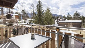 En uteplats med ett bord och stolar, med utsikt över ett snötäckt landskap med byggnader och träd.