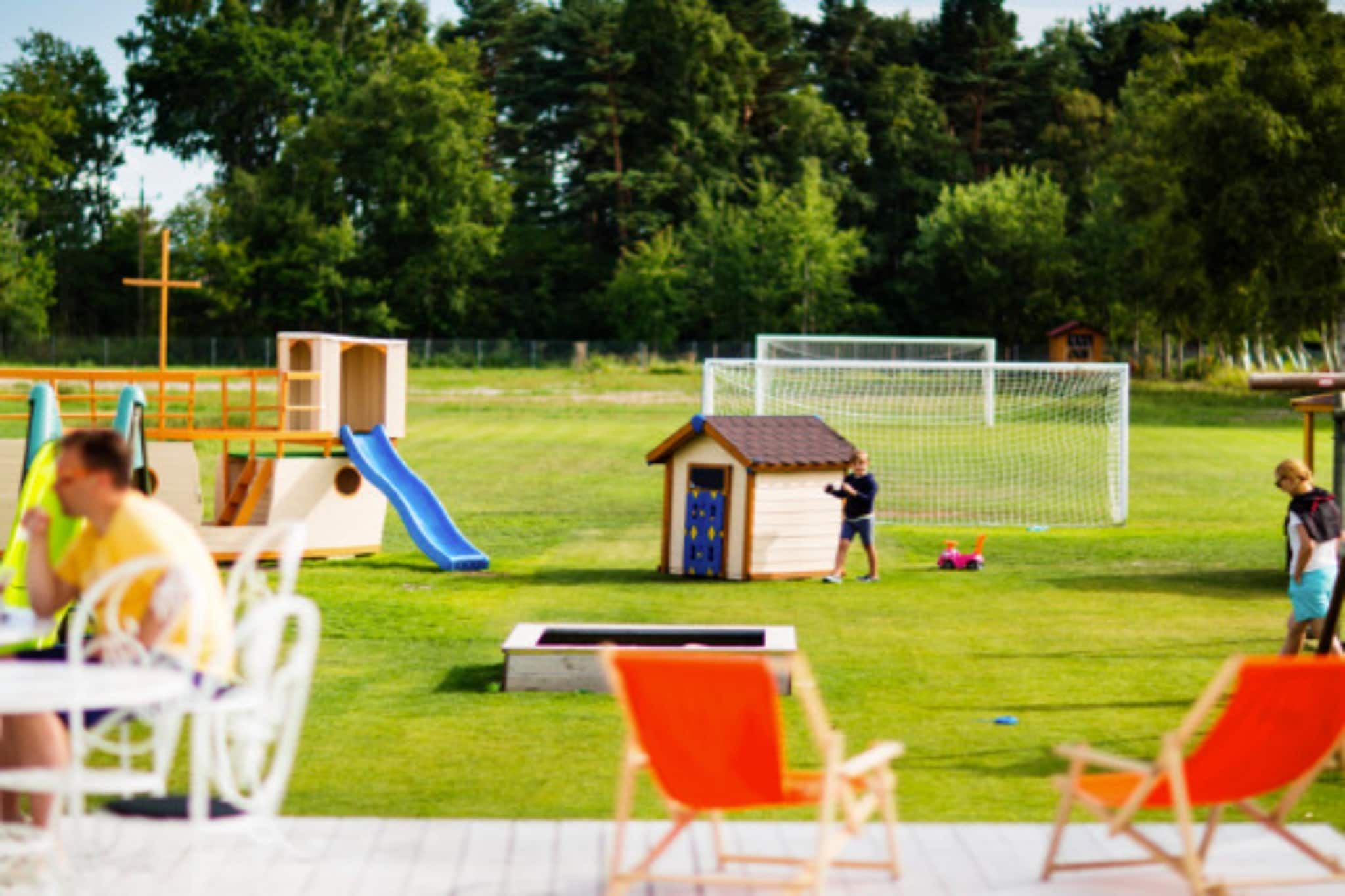 Ein Spielplatz mit Rutsche, einem kleinen Schuppen und einem Fußballtor.