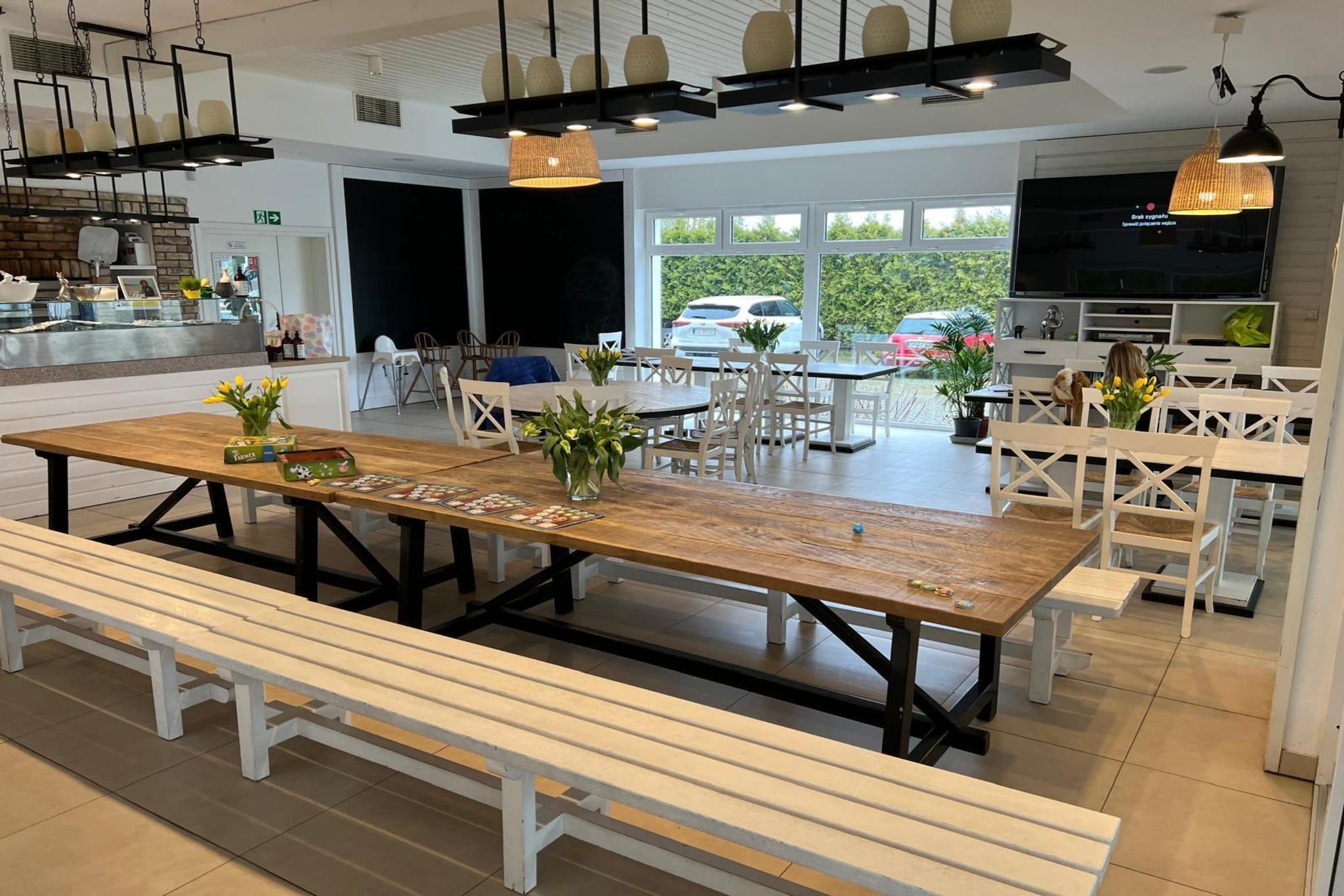 Ett rymligt matområde med ett långt träbord, vita bänkar och en modern takdesign.