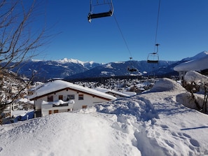 Ein verschneites Bergdorf mit Seilbahnen und einem Gebäude im Vordergrund.