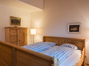 Ein Schlafzimmer mit einem hölzernen Bett, einer Holzkommode und einer Wandlampe.