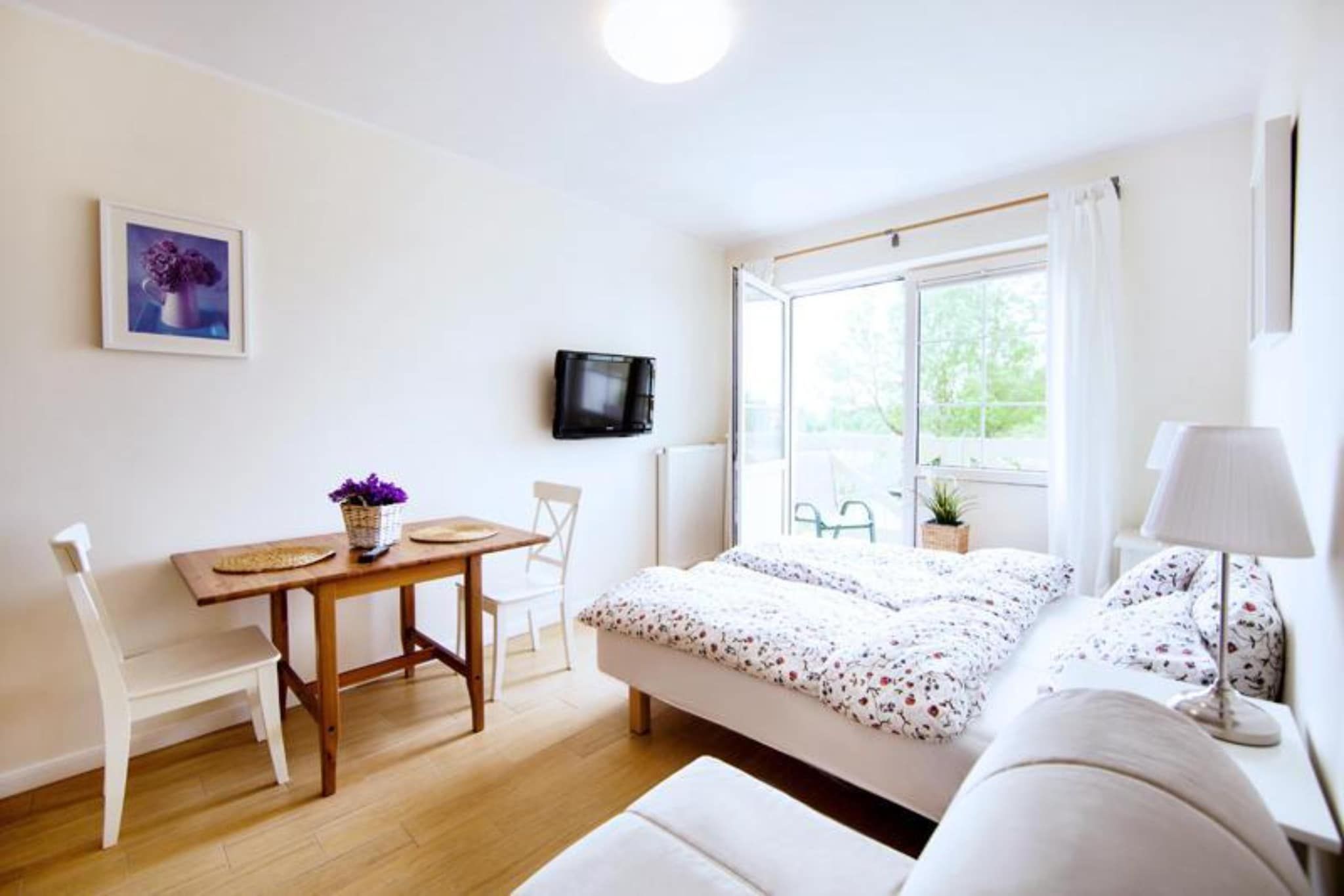 Une chambre avec un lit, une table avec des chaises, un téléviseur et une fenêtre donnant sur un paysage verdoyant.