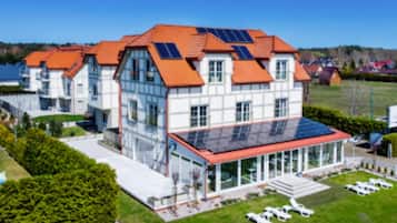 Un bâtiment moderne doté d’une grande façade en verre, de panneaux solaires sur le toit et d’une pelouse bien entretenue avec des espaces de détente en plein air.
