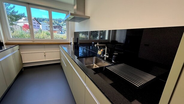 Moderni keittiö, jossa on suuri ikkuna, sisäänrakennettu liesi ja pesuallas.