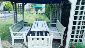 Een overdekt terras met een tafel en bankjes.