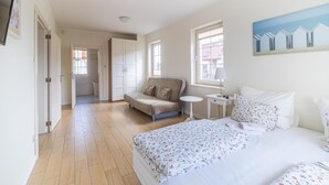 Ein Schlafzimmer mit Bett, Sofa, einem kleinen Tisch und einem Gemälde an der Wand.