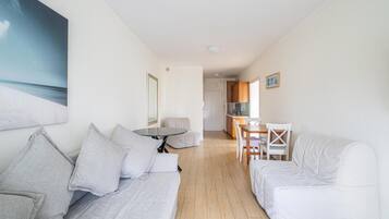 Un salon moderne avec un canapé, une table à manger et des chaises, et une cuisine en arrière-plan.