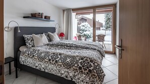 Une chambre à coucher avec un lit, des tables de chevet, une fenêtre et une vue sur l’extérieur.