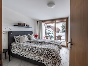 Een slaapkamer met een bed, nachtkastjes, een raam en uitzicht op buiten.